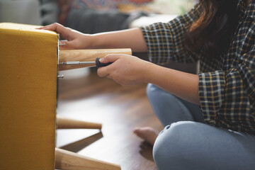 Women tighten screw with screwdriver equipment for assembling leg of chair and making furniture
