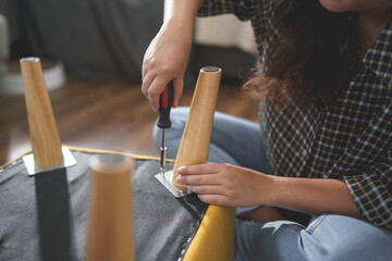 Women tighten screw with screwdriver equipment for repairing leg of chair and assembling furniture