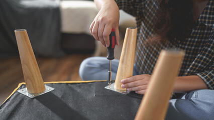 Women tighten screw with screwdriver equipment for repairing leg of chair and assembling furniture