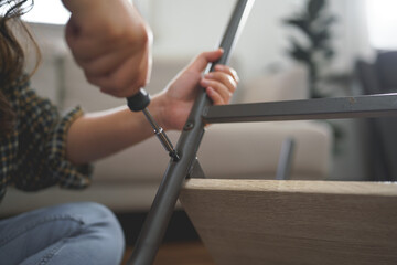 Women use screwdriver equipment to tighten screw while repairing leg of chair and making furniture