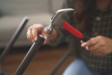 Women using hammer equipment to assembling and repairing chair while making furniture for new house