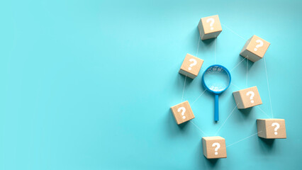 QnA or questions and answers concept. Blue magnifying glass with question symbol on wooden cube over a blue background with copy space . - obrazy, fototapety, plakaty
