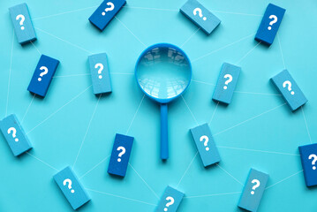 QnA or questions and answers concept. Blue magnifying glass with question symbol on wooden cube over a blue background. - obrazy, fototapety, plakaty