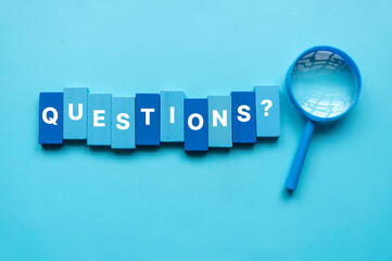 QnA or questions and answers concept. Blue magnifying glass with text over a blue background.