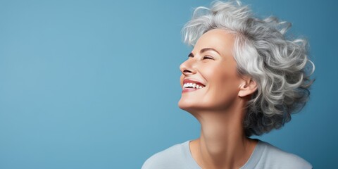 Portrait of a happy smiling Scandinavian woman in her 50s. Luxurious middle-aged woman with a short gray hairdo looking at copy space. Photo on blue background.