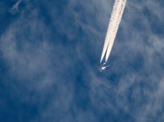 青空と太陽が反射した機体と飛行機雲