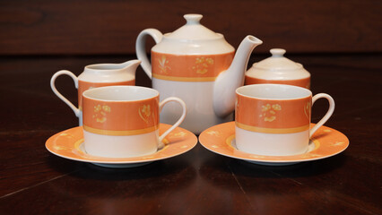Teapot set as seen from above on a dark wood dining room table.