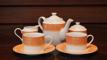 Teapot set as seen from above on a dark wood dining room table.