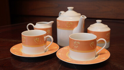 Teapot set as seen from above on a dark wood dining room table.