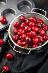 Cherry cake. Cupcakes with cherries. Cherry summer background. A large number of cherries with leaves on the table on a black background. close-up.