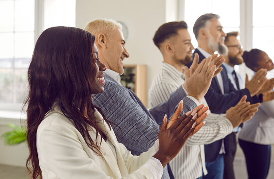 Business people clapping their hands at meeting or conference in office. Office team in formal wear applauding while standing in line at seminar, workshop. Teamwork, corporate coaching