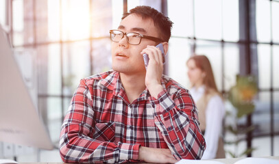 Businessman talking on smartphone and working in office.