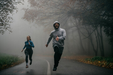 Front view of joggers sprinting through the fog, capturing the essence of movement and mystery.