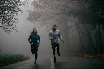 Front view of joggers sprinting through the fog, capturing the essence of movement and mystery.