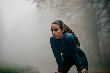 Close-up of a runner's determined expression as she pushes through the fog, determination clear in...