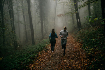 Two friends in stylish activewear jog together, their camaraderie illuminated by the mist.