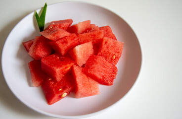 Freshly sliced watermelon on a white plate with a wood pattern background