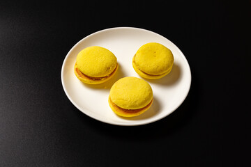 Yellow macaroons on a white plate.