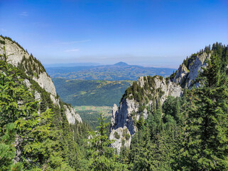 Landscape in the Piatra Craiului Mountains part of the Carpathian range , steep cliffs and fir forest with the Transylvania plateau in the background