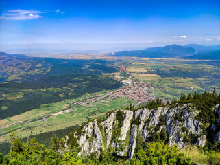 Wide panoramic view from the peaks of the Piatra Craiului Mountains , with Zarnesti city and other inhabited areas , the hills of the Transylvanian plateau , Romania