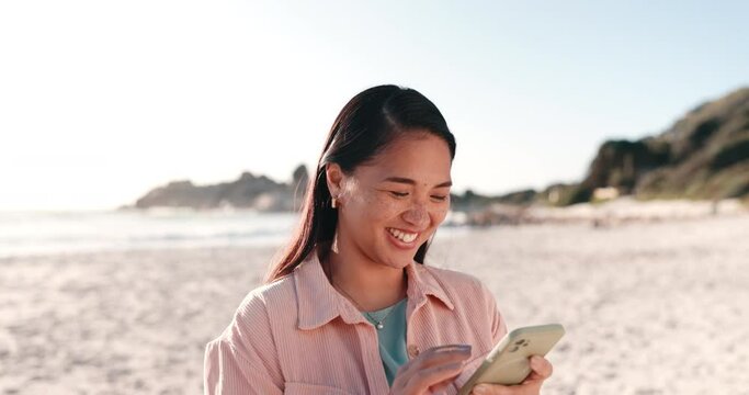 Happy woman, phone and beach for holiday, vacation and social media or funny internet meme by ocean. Young asian person scroll or chat on mobile for communication, travel information and blog by sea