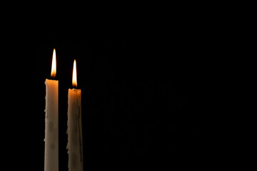Two lit white candles with copy space on black background