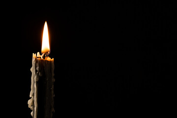 Lit white candle with copy space on black background