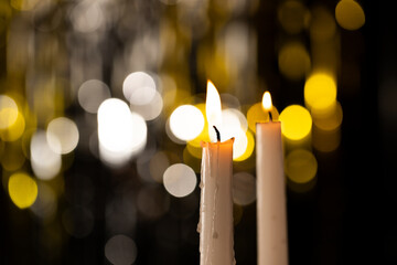 Two lit white candles and bokeh with copy space on black background