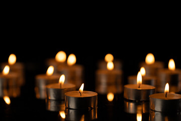 Lit tea candles with copy space on black background
