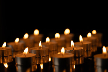Rows of lit tea candles with copy space on black background