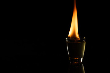 Lit candle in glass container with copy space on black background