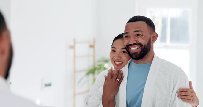 Hug, smile and young couple in the bathroom for health, wellness and morning routine together. Happy, mirror and interracial man and woman embracing before self care treatment at modern apartment.