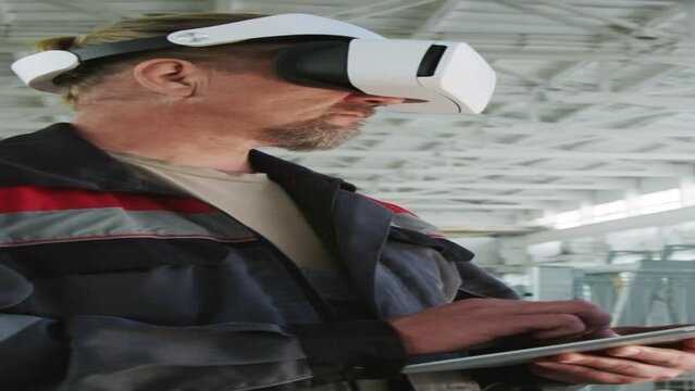Vertical shot of male factory inspector using digital tablet and VR headset during workdayVertical shot of male factory inspector using digital tablet and VR headset during workdayVertical shot of mal