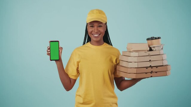 Delivery woman in uniform holding stack of pizza boxes with coffee and smartphone. Advertising area, workspace mockup.