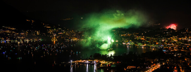 Panoramic night view of the lake of Lugano celebrating Switzerland's National Day with fireworks everywhere