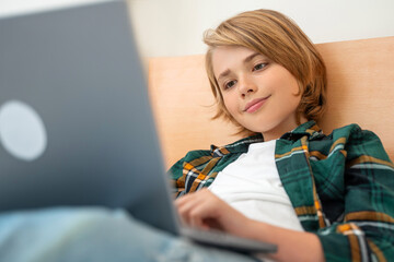 Smart caucasian middle School child boy using laptop. Child typing on the keyboard. Play video game.Online tutor teaching digital class, web lesson on computer at home. Virtual education. E-education.