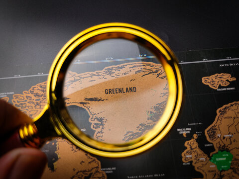 Hand holding vintage magnifying glass and focus to GREENLAND map - Powered by Adobe