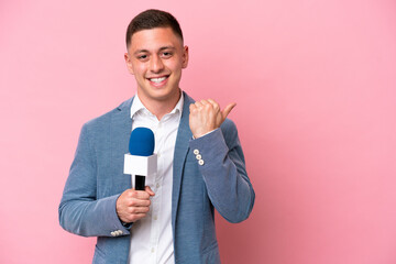 Young brazilian presenter man isolated on pink background pointing to the side to present a product