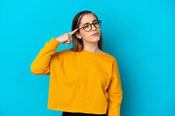 Young caucasian woman isolated on blue background making the gesture of madness putting finger on the head