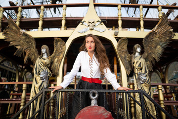 a beautiful girl in a pirate costume on the deck of a ship.