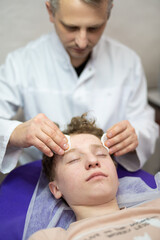 Obraz na płótnie Canvas a cosmetologist doctor makes cosmetic procedures on the face of a young guy in a beauty salon
