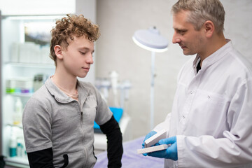 Obraz premium A man doctor talks to his boy patient and advises him on medicine