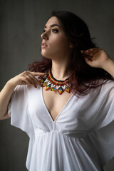 a beautiful young girl in a white dress with a handmade jewelry necklace around her neck