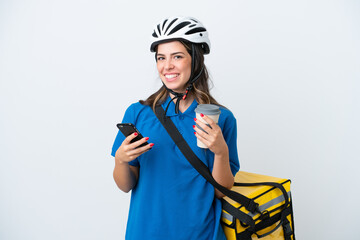 Young delivery woman with thermal backpack isolated on white background holding coffee to take away and a mobile