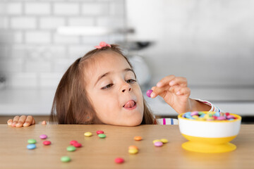 Young girl grabbing candy on kitchen table