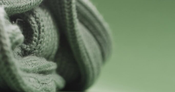 Micro video of close up of green wooly crochet fabric with copy space on green background