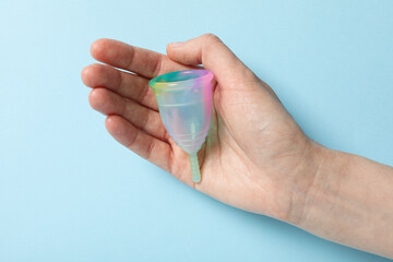 Menstrual cup in hand on blue background