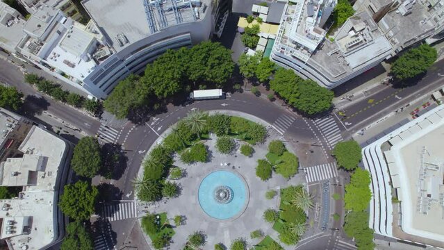 Dizengoff Square to the Tel Aviv beaches on a hot summer day as people sit and enjoy the shade of the square's trees - top down to tilt up shot