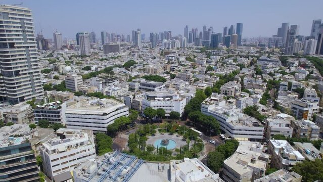 Circling around Dizengoff Square while pedestrians walk by a fountain in the center of the square - Parallax shot