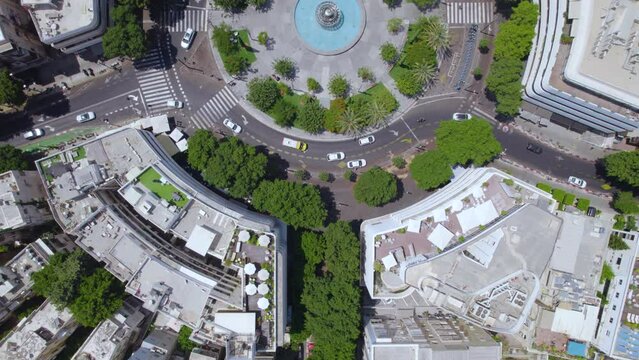 Cruising over Zamenhoff Street, Dizengoff Square and Beilinson Street on a hot summer day when people are sitting under the trees - top down view